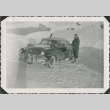 Man standing by a car in the snow (ddr-densho-321-304)