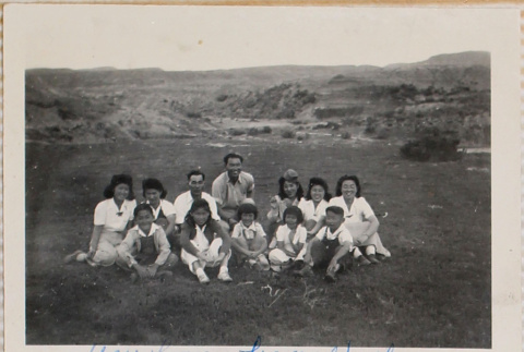 Twelve adults and children sitting in field (ddr-densho-464-55)
