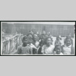 Photograph of children at Manzanar standing next to a fence and in front of a barracks (ddr-csujad-47-81)