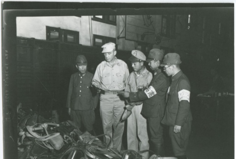United States and Japanese soldiers looking at confiscated equipment (ddr-densho-299-2)