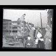 Japanese American family from Terminal Island unloading from the bed of a truck as military police watch on (ddr-csujad-54-3)