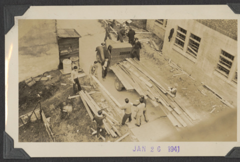 Workers unload lumber from a truck (ddr-sbbt-4-85)