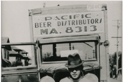 A man sitting on one of the many trucks used by the Pacific Beer Distributors (ddr-densho-353-148)