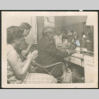 Man sitting at desk, with two women behind him (ddr-densho-293-196)