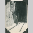 Man standing at entrance to tunnel by icicles (ddr-ajah-2-323)