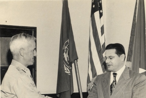 Two men shaking hands and exchanging a document (ddr-njpa-2-1122)