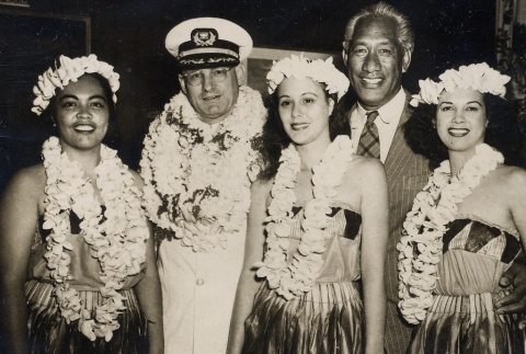 Duke Kahanamoku and a naval officer posing with three young women wearing leis and Hawaiian dress (ddr-njpa-2-494)