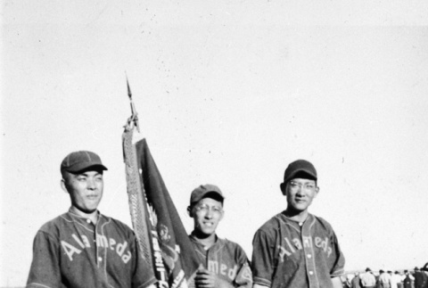 Three men in baseball uniforms with flag (ddr-ajah-5-92)