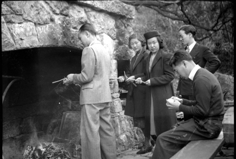 Two women and three men standing by large outside fireplace (ddr-densho-426-1966)