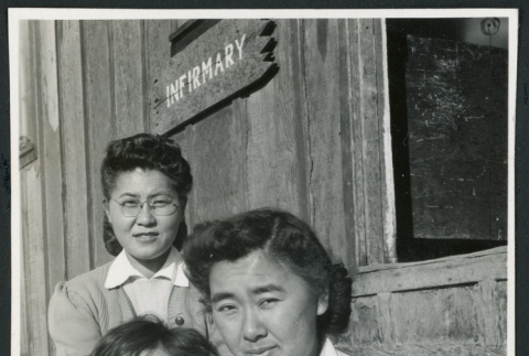 Photograph of two women an a young child posing in front of the infirmary at Cow Creek Camp in Death Valley (ddr-csujad-47-135)