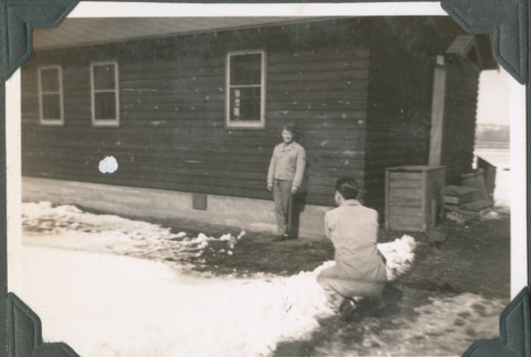 Man taking photo of another man outside camp building (ddr-ajah-2-468)