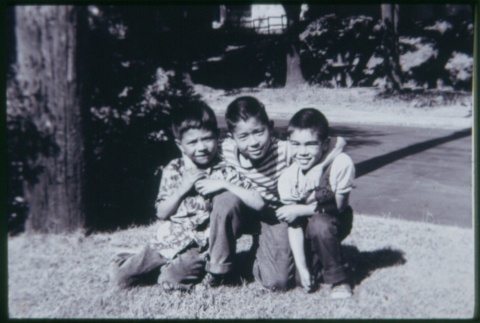 Three boys kneeling on grass (ddr-densho-330-131)