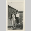 Two women posing in front of barracks (ddr-manz-7-26)