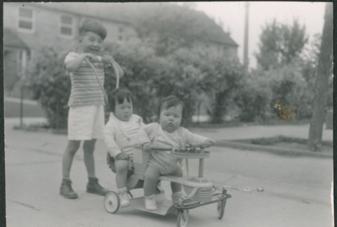 Boy pushing two children on a stroller (ddr-densho-523-184)