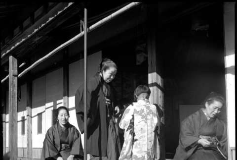 Three women and child seated outside house (ddr-densho-426-310)