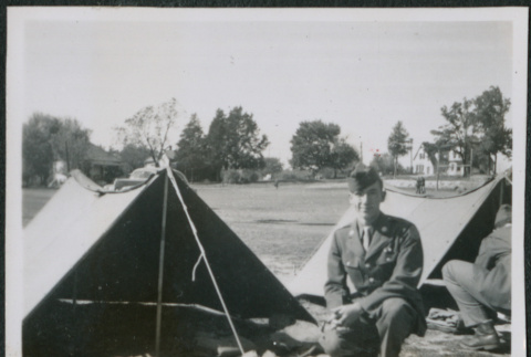 Man sitting next to tent with gear (ddr-densho-434-463)