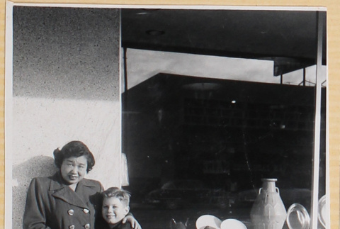 Woman with boy on crutches outside shop (ddr-densho-522-26)