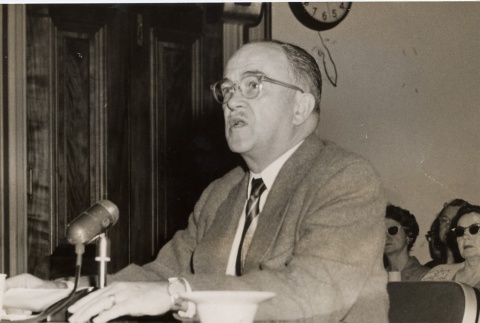 Man seated speaking into a microphone (ddr-njpa-2-829)