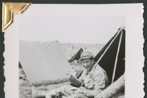 Man sitting outside small tent, eating (ddr-densho-434-82)