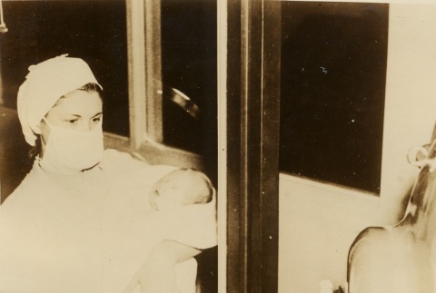 Nurse showing a baby to a person in an iron lung (ddr-njpa-1-1932)