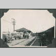 Men in uniform standing alongside train tracks with station in background (ddr-ajah-2-271)