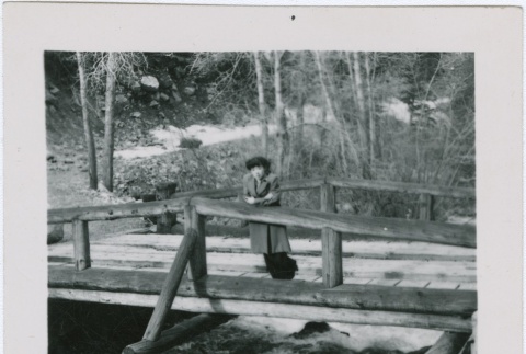 Guyo Tajiri standing on a bridge over a creek (ddr-densho-338-263)
