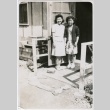 Two girls standing in front of barracks (ddr-densho-292-1)