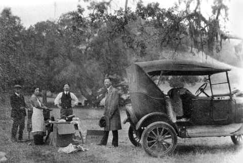 Group at a picnic standing by car (ddr-ajah-6-567)