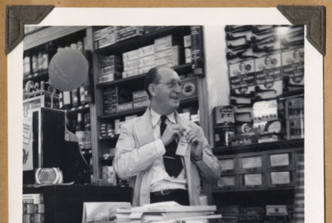 Man standing behind a shop counter (ddr-densho-542-94)