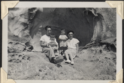 Couple with two children sitting in rocky alcove.  Likely Tom Nobuo Yamashita, Sadie (Muromoto) Yamashita and their two children (ddr-densho-466-925)