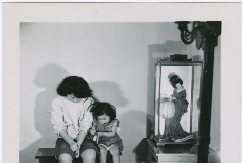 A woman and young girl seated next to a Japanese doll (ddr-densho-338-16)