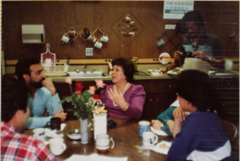 Woman telling story to others seated at table (ddr-densho-426-1277)