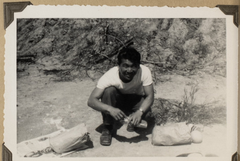 Sam kneeling next to paper bags (ddr-densho-542-485)