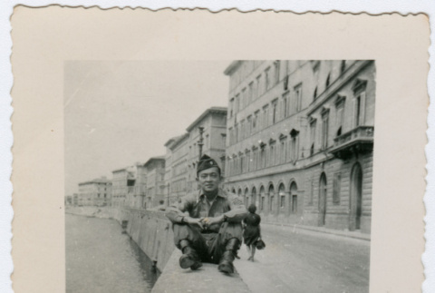 Soldier sitting on wall near water in Italy (ddr-densho-368-52)