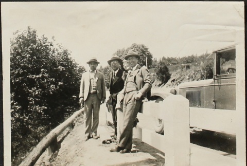 Issei men and a woman standing by a guard rail (ddr-densho-259-214)
