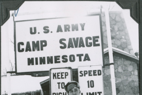 Man standing by Camp Savage sign.  Signed on from: George (ddr-ajah-2-463)