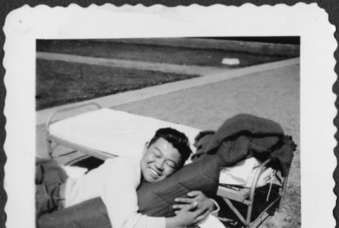 Man laying on cot with gear outside (ddr-densho-434-420)