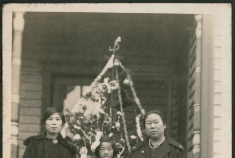 Two women and a girl holding a doll by Christmas tree (ddr-densho-293-73)