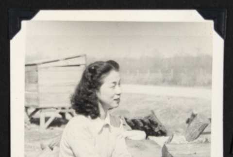 Woman seated beside a wood pile (ddr-densho-542-716)
