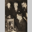 A group of men looking at an object on a desk (ddr-njpa-4-174)