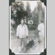 Man standing with trees in background.  Signed on front:  A friend / Richard Omori (ddr-ajah-2-547)