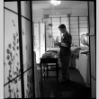 Man standing by table surrounded by shoji screens (ddr-densho-426-2474)