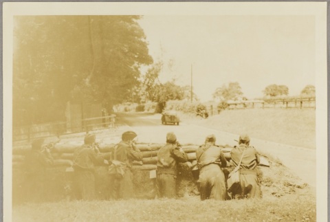Soldiers behind a roadside barricade aiming rifles at a car (ddr-njpa-13-1491)