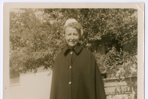 Nurse standing in front of stone wall and trees (ddr-densho-515-1)