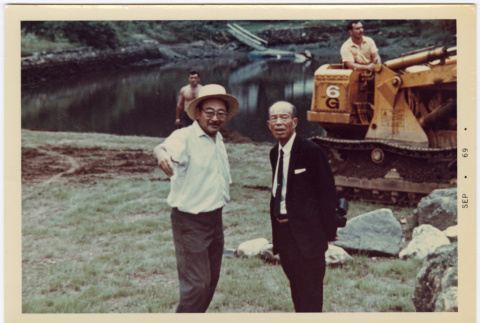 Kaneji Domoto (in hat) and unidentified man by pond with bulldozer (ddr-densho-377-1345)