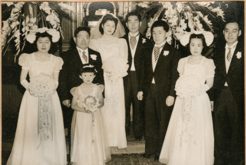 Henri Takahashi and Tomoye (Nozawa) Takahashi standing at altar with wedding party (ddr-densho-410-490)