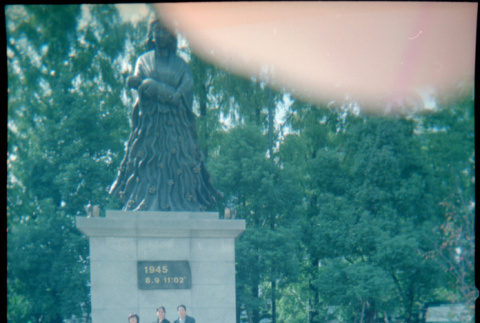 Tomoye, Masako and Norman (?) standing before statue (ddr-densho-426-502)