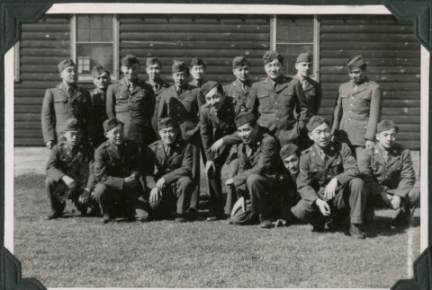 Men in uniform posing for group photo outside camp buildings (ddr-ajah-2-531)