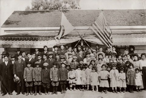 Large group posing in front of building with Japanese and U.S. flags (ddr-ajah-6-726)