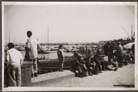 Men sitting alongside bay by boats (ddr-densho-466-90)